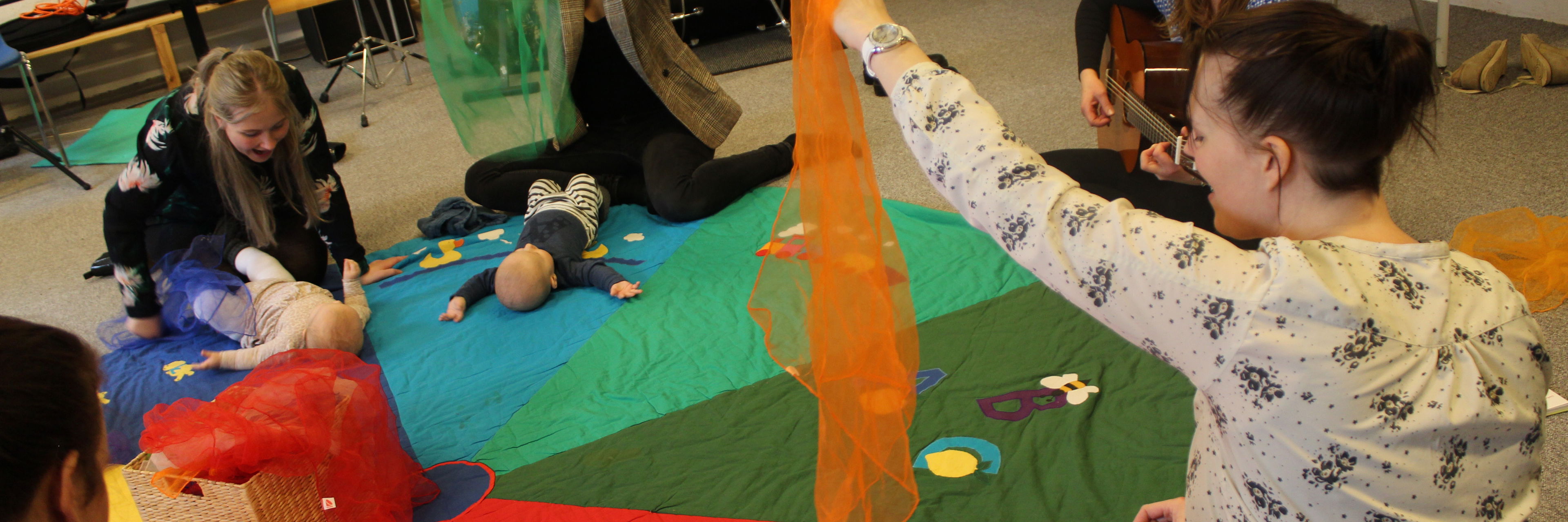 Billede af mødre med babyer og musiklærer med guitar